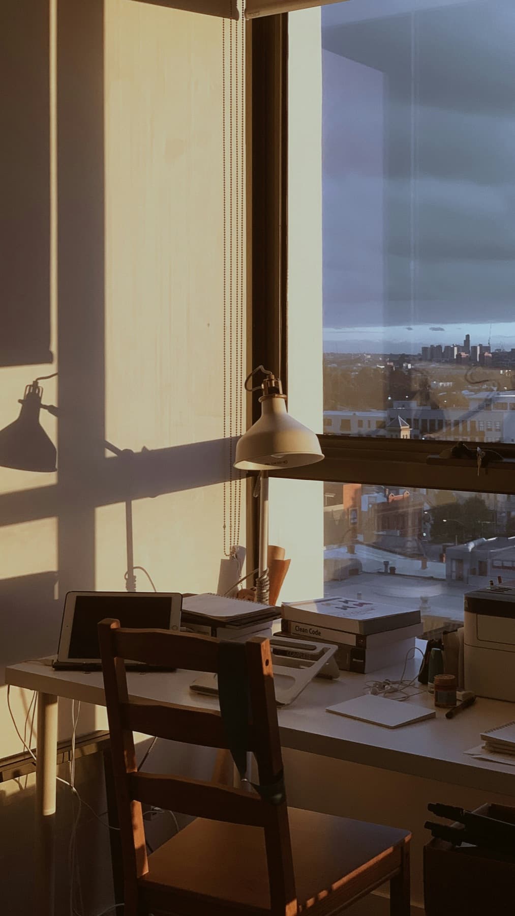 Quiet desk by a tall window above the Melbourne skyline at golden hour