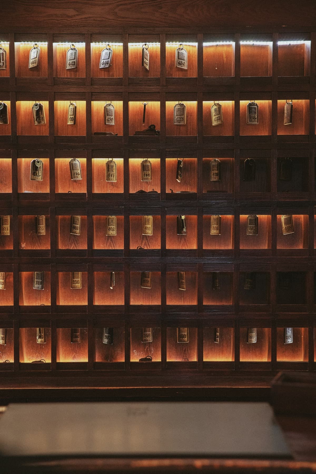 Hotel key wall in Wuzhen, China, with brass-tagged room keys in warm backlit wooden cubbies