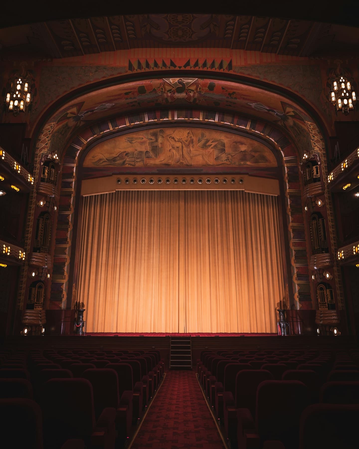 Empty Art Deco auditorium of the Tuschinski Theatre, Amsterdam, with a lit gold curtain
