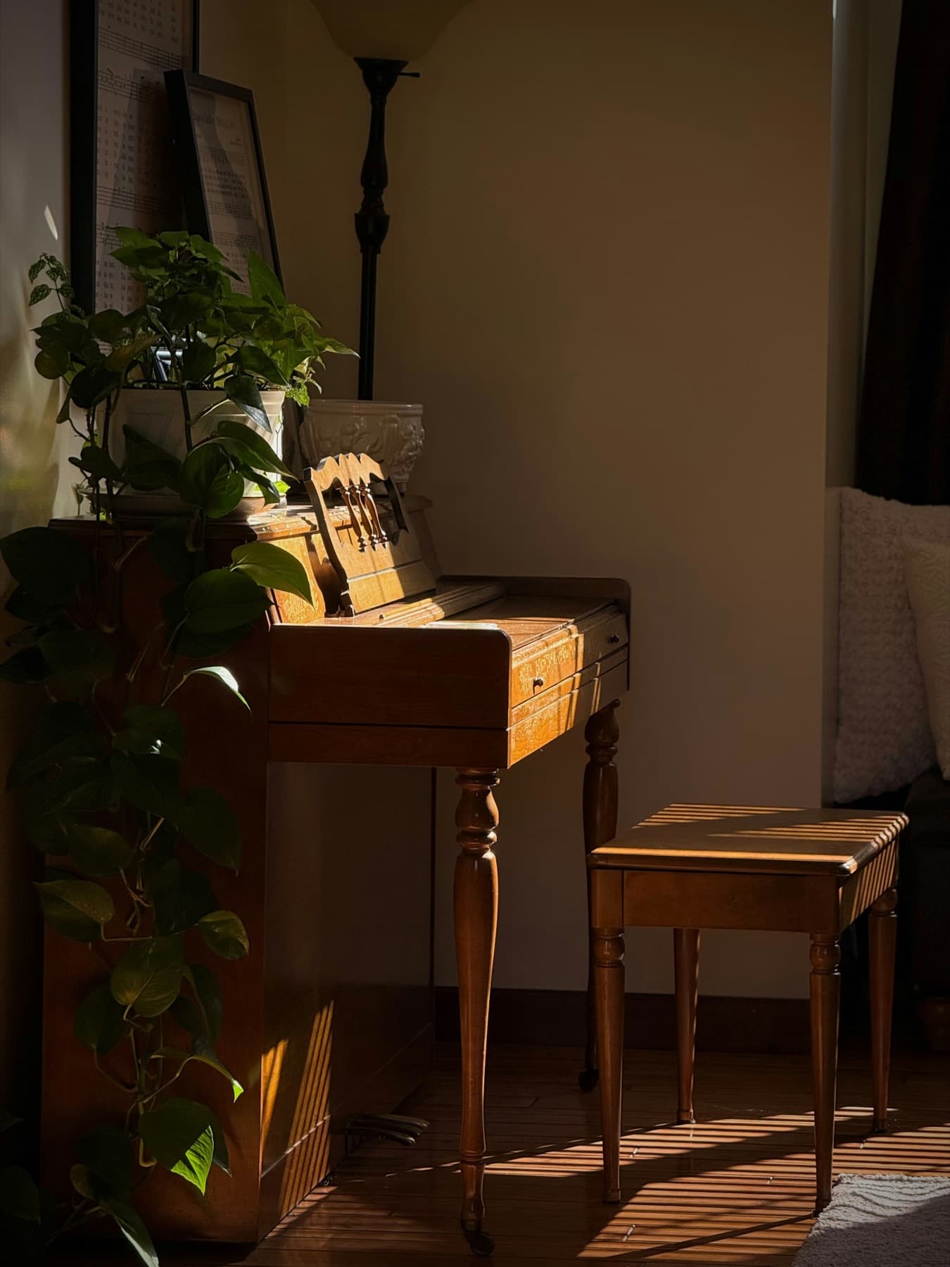 Antique wooden upright piano and stool in a dim room crossed by a shaft of golden light