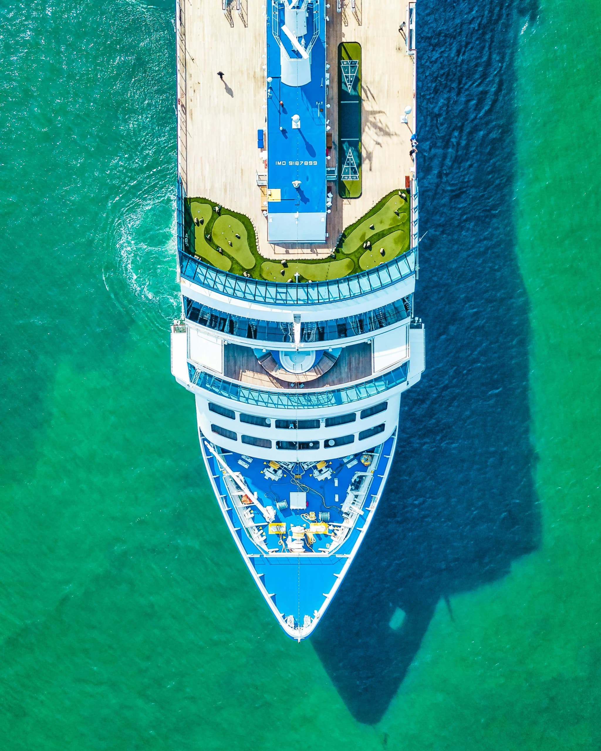 Aerial view of a cruise ship sailing turquoise tropical water
