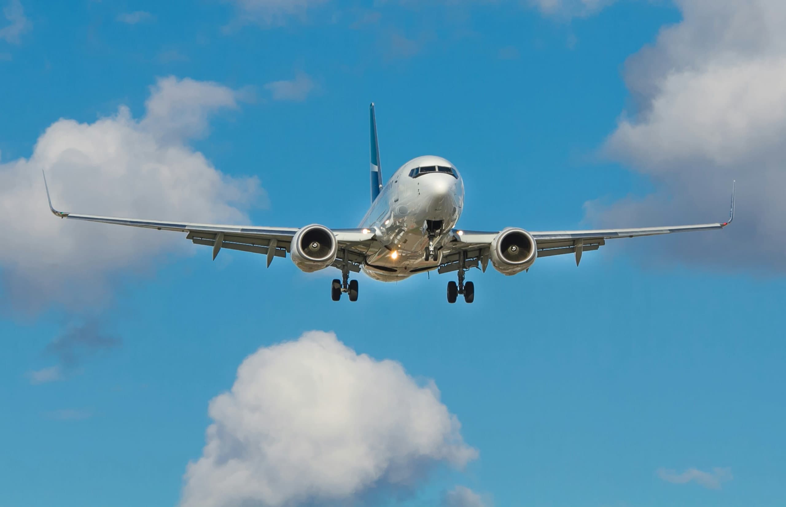 Commercial airliner coming in to land against a blue sky with clouds