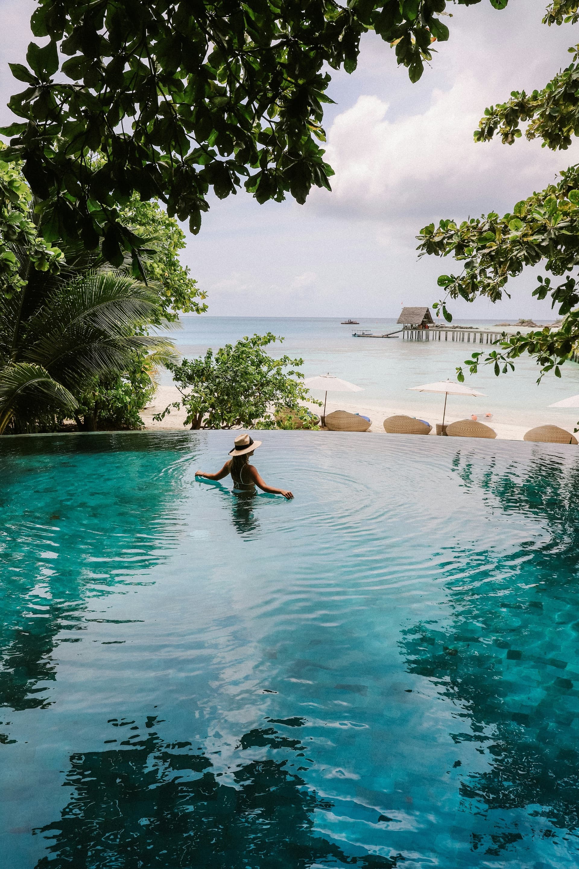 Traveler relaxing in a beachfront infinity pool at a tropical island resort